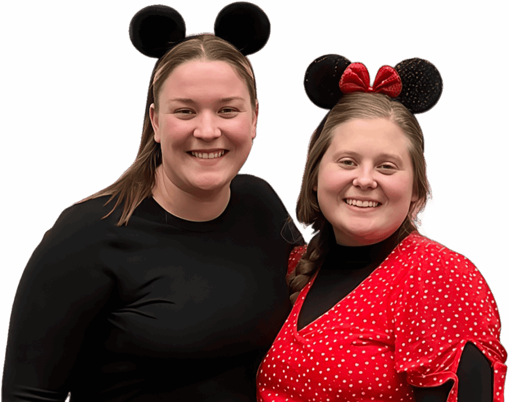 Two teachers smiling together wearing Mickey and Minnie ears on a fun themed background.